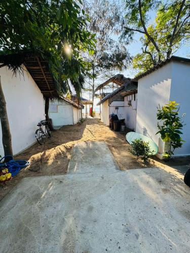 a dirt road between two buildings with trees at Beach Wave Hotel in Arugam Bay