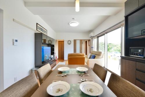 a dining room with a table and a television at サンシティ in Kitanakagusuku