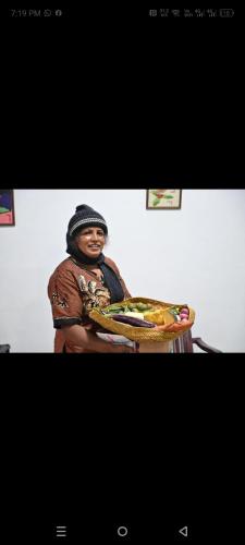 a woman sitting in a chair holding a plate of food at Adisham village home in Haputale