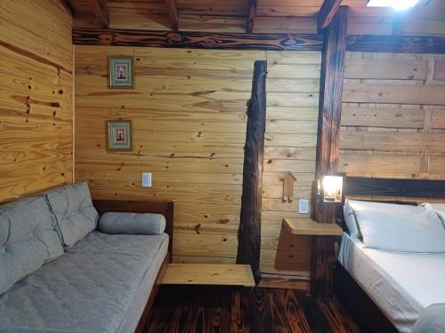 a room with a bed and a couch in a log cabin at Cabañas Lignum Tiny House in La Granja