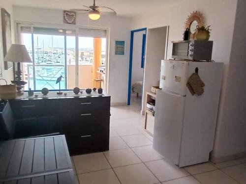 une cuisine avec un réfrigérateur blanc et une fenêtre dans l'établissement Appartement T2 Frontignan-Plage, 6 pers, vue port, parking inclus - FR-1-785-17, à Frontignan