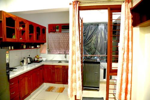 a kitchen with red wooden cabinets and a window at The Aster Apartment in Trivandrum