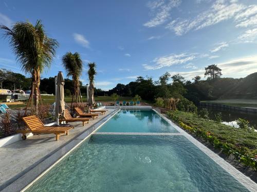 une piscine avec des chaises et des palmiers dans l'établissement The Oiia Lakeview A'Famosa, Resort Melaka, à Simpang Empat