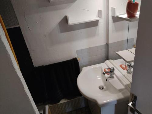 La salle de bains est pourvue d'un lavabo blanc et d'une serviette noire. dans l'établissement Gruissan: 4 Pers, Clim, Parking, Proche Centre - FR-1-796-81, à Gruissan