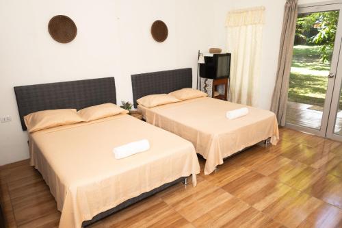 two beds in a white room with wooden floors at Chaikoni Lodge in Pucallpa