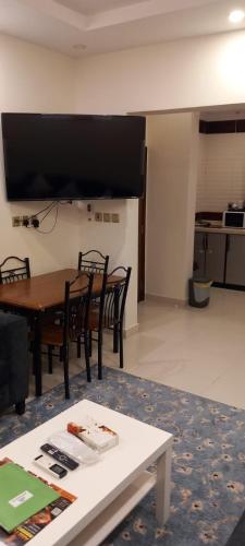 a living room with a table and chairs and a tv at شقق البيت الجديد - شقق مخدومه in Yanbu