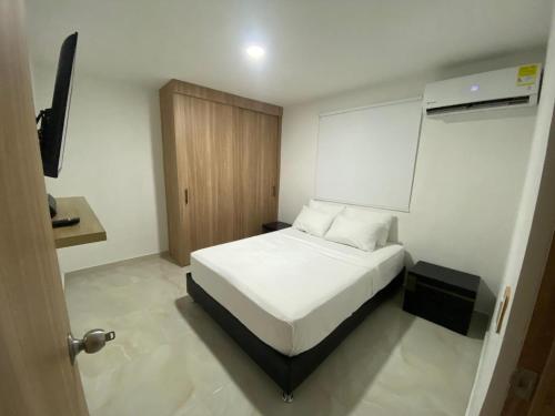 a bedroom with a white bed and a wooden door at Apartamento Sabaii 201 in Cartagena de Indias