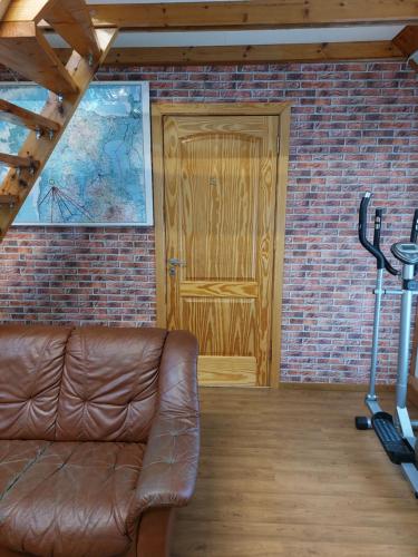 a brown leather couch in front of a wooden door at Livonia Matkamaja in Kilingi-Nõmme