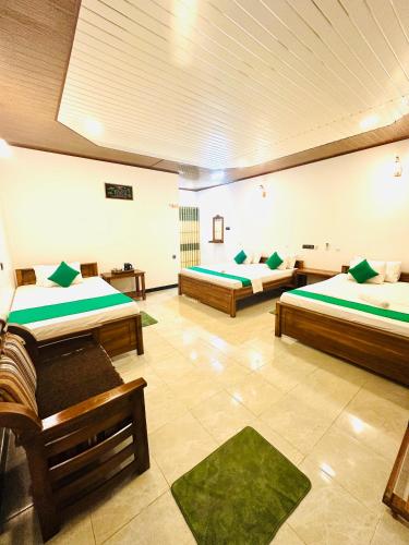 a large room with two beds and green pillows at Ceylon Safari Cottage in Udawalawe