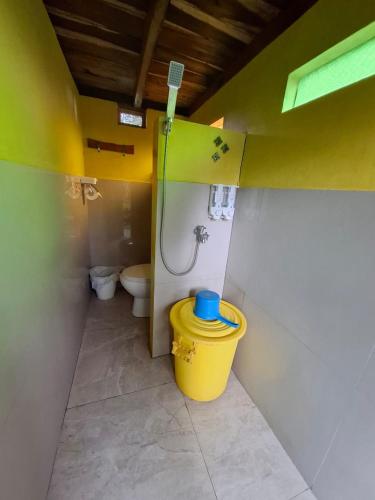 a bathroom with a toilet and a yellow bucket at Omah Kepel Yogyakarta in Soprayan