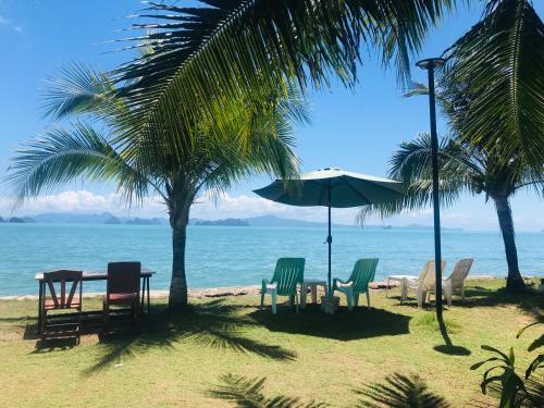 a table with chairs and an umbrella on the beach at Koh Yao Yai Sea Breeze House เกาะยาวใหญ่ซีบรีซเฮ้าส์ in Ko Yao Yai