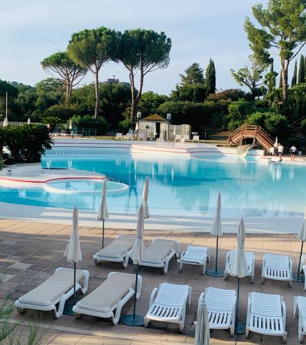 une piscine avec des chaises et des parasols en face de celle-ci dans l'établissement Cap Estérel FH007 JARDIN PRIVATIF ET CLÔTURÉ ,vue Mer,piscines , parking couvert,COUP DE CŒUR, à Saint-Raphaël