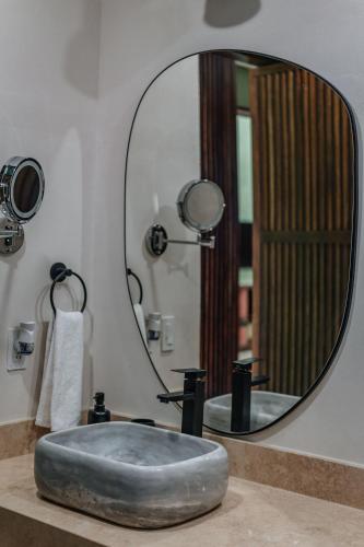 a bathroom sink with a large round mirror at Casa Mara 53 Luxury House in downtown Mérida in Mérida