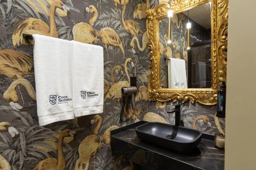 Un baño con lavabo, espejo y toallas. en 5 Sentidos - Suites de Lujo, en Tudela