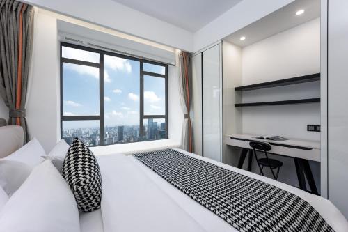 a bedroom with a white bed with a large window at Ode to Joy Hotel Apartment East Railway Station Guanghuan Shopping Park Branch in Chengdu
