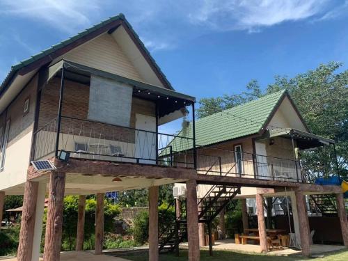 een huis met een veranda rondom met een terras bij Sleepy Lagoon in Mu Si