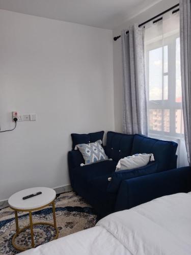 a living room with a blue couch and a table at Relax Crib in Ruiru