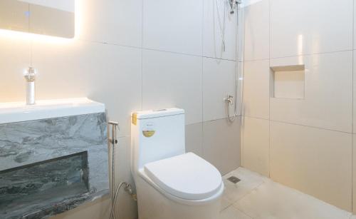 a white bathroom with a toilet and a sink at Stay Manila Hotel by RedDoorz in Manila