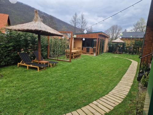 a backyard with a table and an umbrella at Noor House 2 in Şuncuiuş