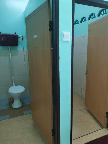 a bathroom with a toilet and a glass door at Annur Homestay 2 in Kampung Padang Maras