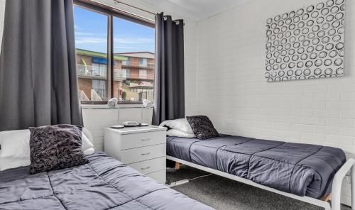 a bedroom with two beds and a window at 2 Bedroom - 2 level apartment - Hydra Holiday Unit 2, Merimbula in Merimbula