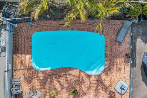 an overhead view of a swimming pool on a brick wall with palm trees at Hydra Holiday Units, Merimbula in Merimbula