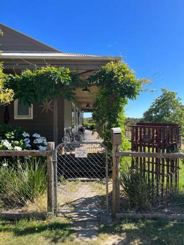 a fence in front of a house with a porch at Woolly Slopes Country Escape in Hepburn Springs