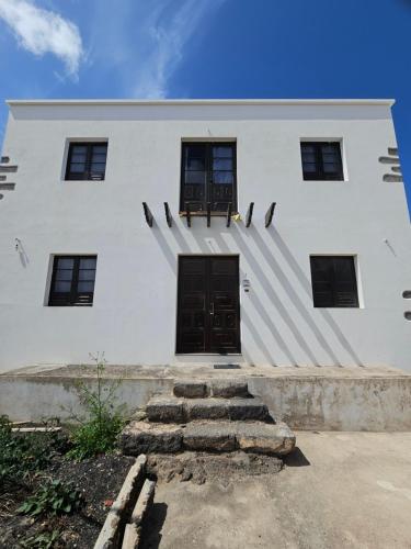 a white building with a black door and stairs at Casona IROKO in La Costa