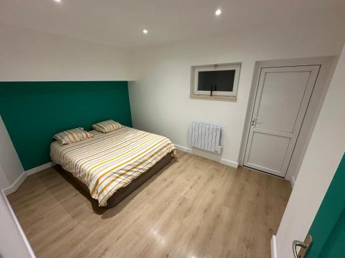 - une chambre avec un lit et un mur vert et blanc dans l'établissement Appartement granville, à Granville