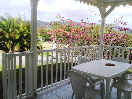 a white porch with a table and chairs and flowers at Antilles Liberte in Sainte-Anne