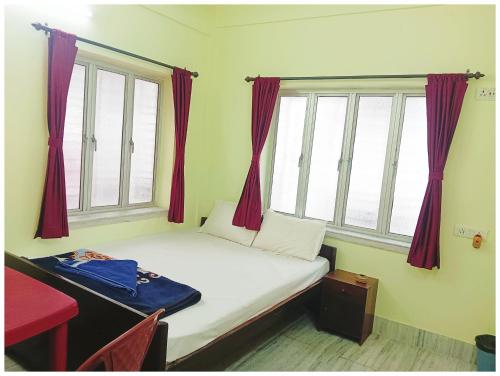 a small bed in a room with two windows at HOTEL PREMIUM PUJA Near Mandirpara JHEEL in Jādabpur