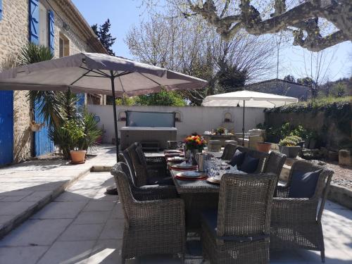 a table with chairs and an umbrella on a patio at MAS PROVENCAL A FLANC DE COLLINE in Bollène