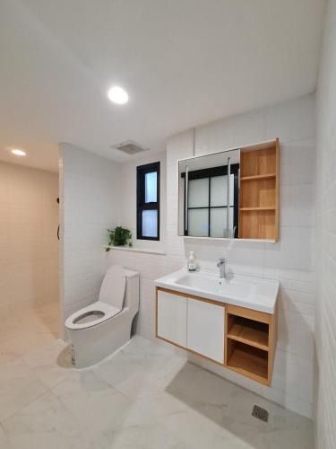 a white bathroom with a toilet and a sink at Wanglang Home in Bangkok Noi