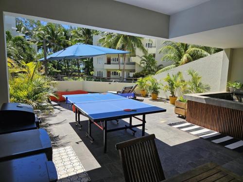 a patio with a table and a blue umbrella at Play - Swim - Dive - Relax - Seaside Recharge in Cap Malheureux