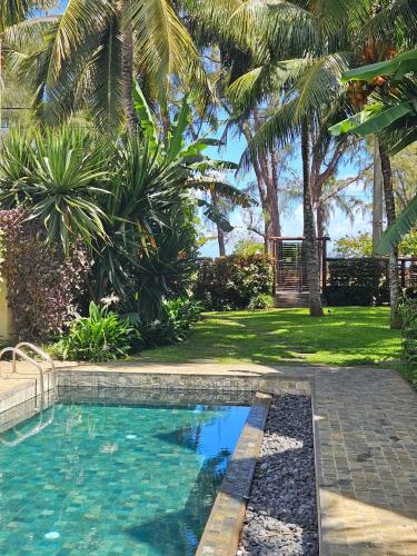 a swimming pool in a yard with palm trees at Play - Swim - Dive - Relax - Seaside Recharge in Cap Malheureux