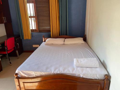 a small bed in a room with a red chair at Bonsai House in Nugegoda