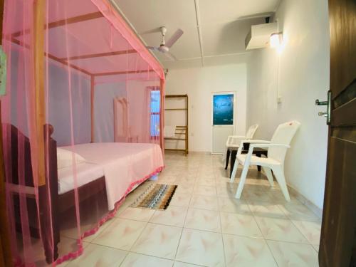 ein Schlafzimmer mit einem rosa Bett sowie einem Tisch und Stühlen in der Unterkunft Neem Trees Unawatuna in Unawatuna