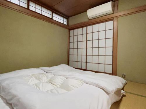 una cama blanca grande en una habitación con ventana en 京都四条河源町みやこ未来, en Kioto