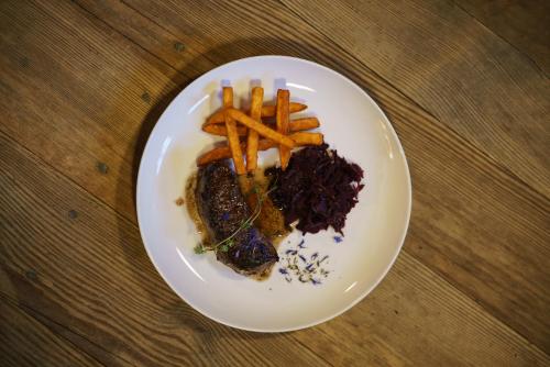a white plate with meat and fries on a table at Chalet Stern in Vipiteno