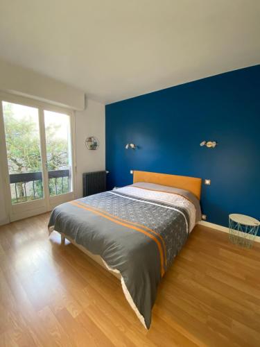 une chambre avec un grand lit avec un mur bleu dans l'établissement Maison piscine Redon, à Redon