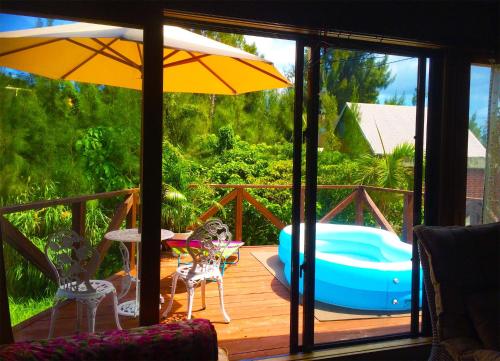 a deck with a hot tub and an umbrella at 猫とピアノと星空のリゾートブティックコテージ -Starry Forest Cottage Okinawa- in Onna