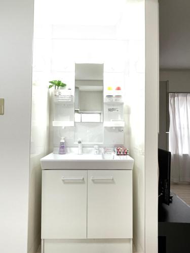 a white bathroom with a sink and a mirror at 結奈希 Yunakis House in Tokyo