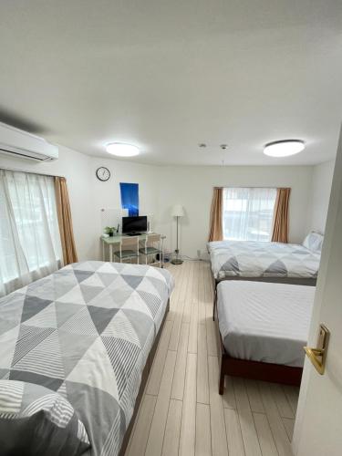 a bedroom with two beds and a desk with a television at 結奈希 Yunakis House in Tokyo