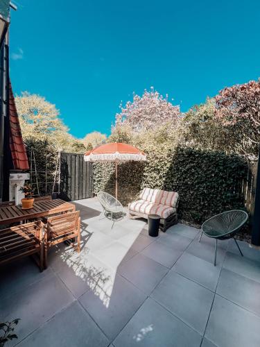 a patio with an umbrella and chairs and a bench at Studio Verver in Bergen