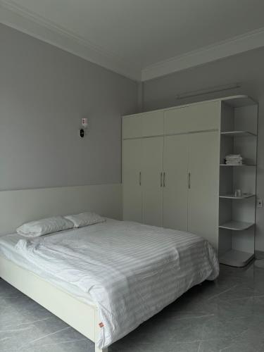 a white bedroom with a white bed and shelves at Táo Homestay in Ha Long