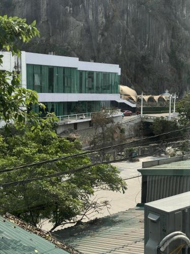 a white building with green windows in front of a mountain at Táo Homestay in Ha Long