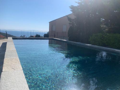 a swimming pool with blue water in front of a building at Vacances de rêve vue mer et montagne in Brando