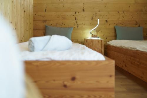 two twin beds in a wooden room with a lamp at Chalet Stern in Vipiteno