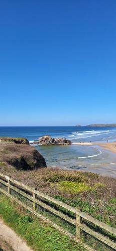 a view of a beach with a fence and the ocean at Sunset retreat caravan with large wrap around decking in Newquay
