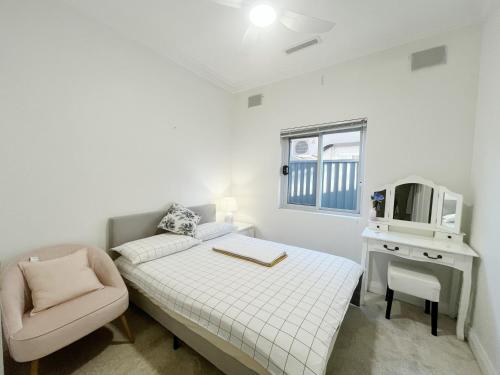 a small white bedroom with a bed and a chair at Small Room B of South Bay Beach and AirPort in Sydney